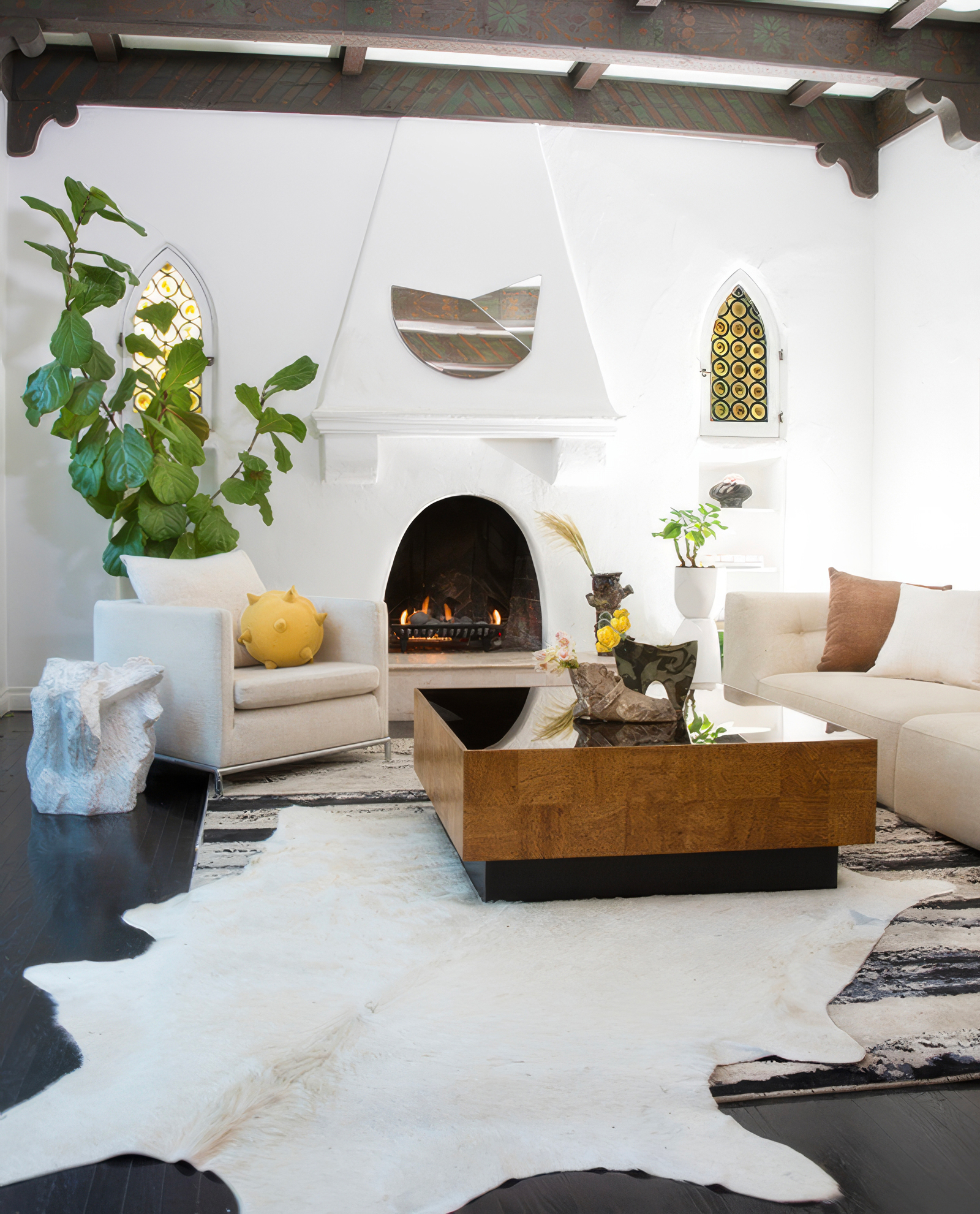 Kim Colwell Design interior design Los Angeles — living room with arched fireplace, cream armchair, and sculptural stone accent, as featured in Interior Design magazine