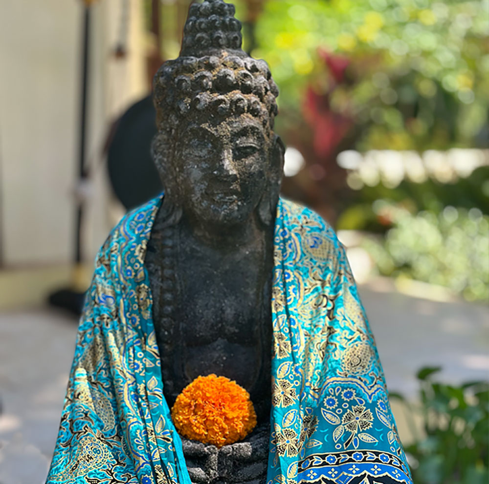 Buddha statue in a blue sarong, orange marigold flower, the tone is set for Kim Colwell Design House Blessing Ceremony, Los Angeles. 